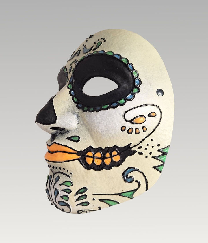 A colorful, intricately decorated Day of the Dead mask with a white background and various patterns and designs.